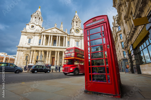 Photography London, England - Traditional red telephone box with iconic red vintage double-decker bus on the move at St