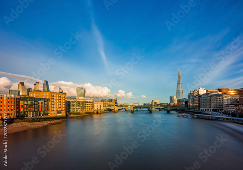 London, England - Panoramic skyline view of central London with skyscrapers of Bank district, sightseeing boat on River Thames, Tower Bridge and other famous landmarks at sunset
