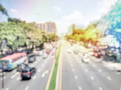 blurred image of traffic jam on the road and opposite side of the road is empty road with green environment and modern building in Bangkok, Thailand . busy road in the morning