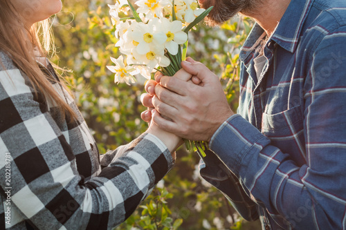 Boy and girl show love and pure feelings for each other. Woman smiling and hugging Man holding flower bouquet.
