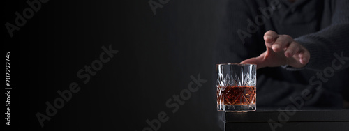 Tablou pe pânză Man's hand reaches for a glass of alcohol.