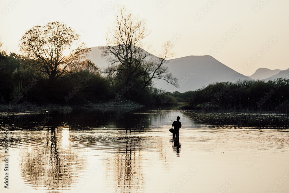 Fisherman in the lake at sunset