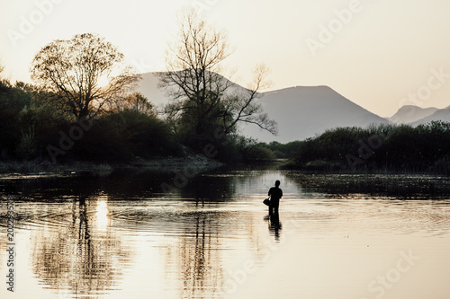 Fisherman in the lake at sunset