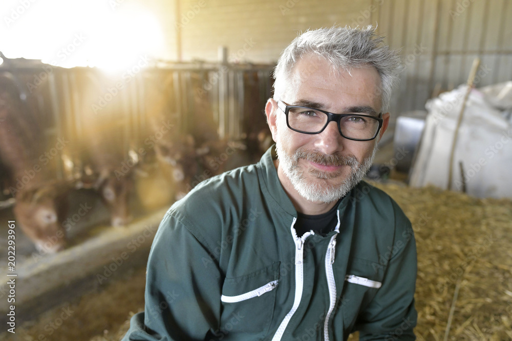 Smiling farmer standing in cow shed Smiling farmer standing in cow shed