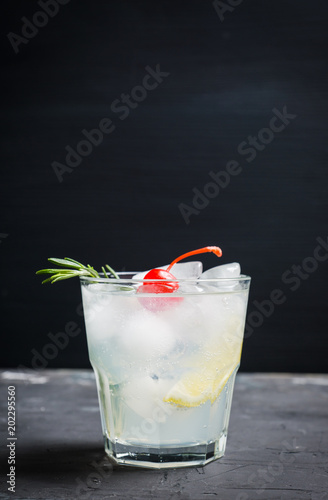 Bitter old-fashioned cocktail with lemon slice and cherry. Selective focus.