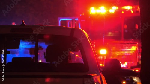 Flashing red  and blue emergency lights  seen through car's interior silhouette at night. Fire truck in background. 4K UHD.