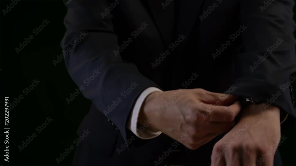 Businessman straighten sleeves shirt and jacket isolated on black background Businessman straighten sleeves shirt and jacket isolated on black background