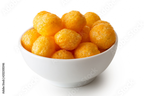 Extruded puffed cheese balls in white ceramic dish isolated on white.