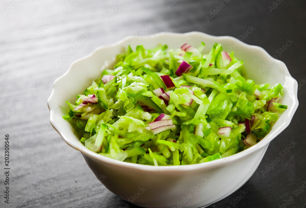 fresh vegetables salad with cabbage, onion and cucumber in bowl on a dark wooden background fresh vegetables salad with cabbage, onion and cucumber in bowl on a dark wooden background