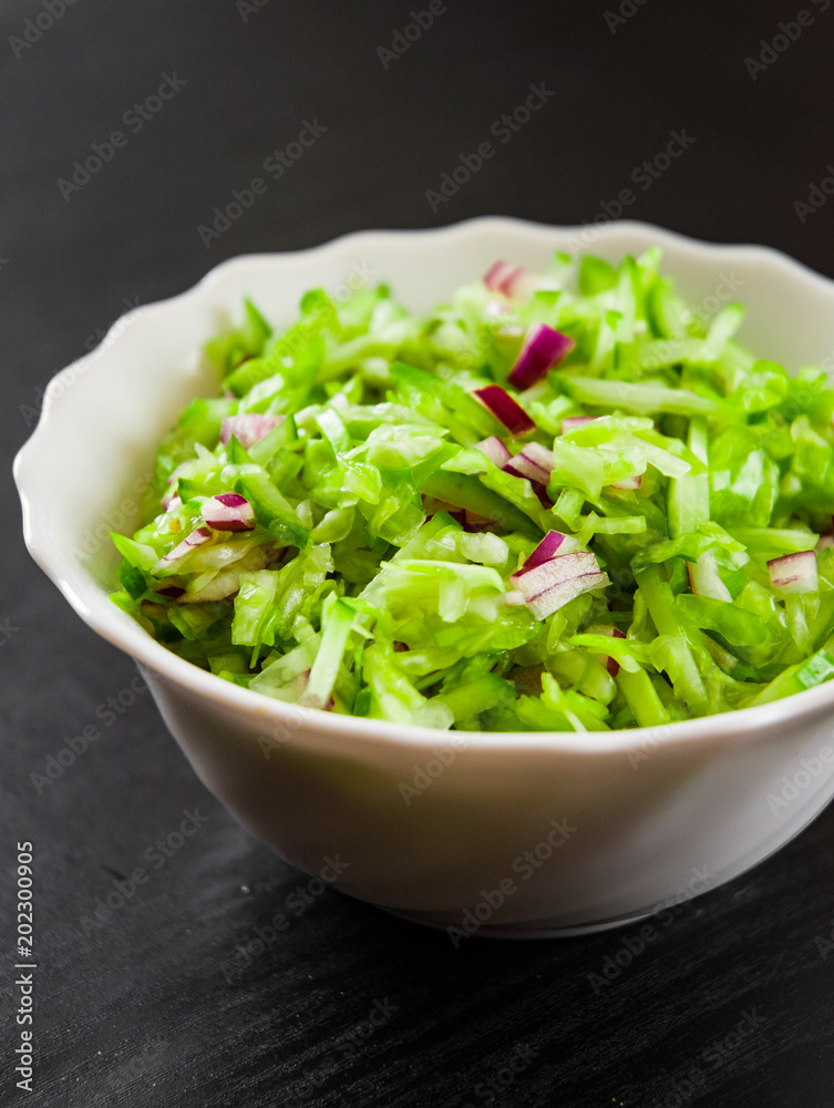 fresh vegetables salad with cabbage, onion and cucumber in bowl on a dark wooden background fresh vegetables salad with cabbage, onion and cucumber in bowl on a dark wooden background