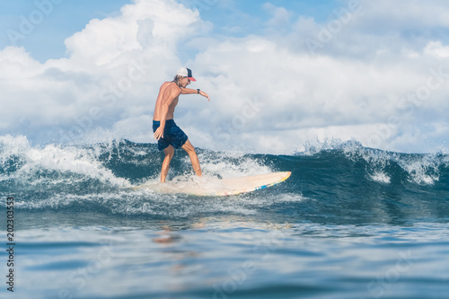 man in swimming shorts and cap surfing in ocean © LIGHTFIELD STUDIOS