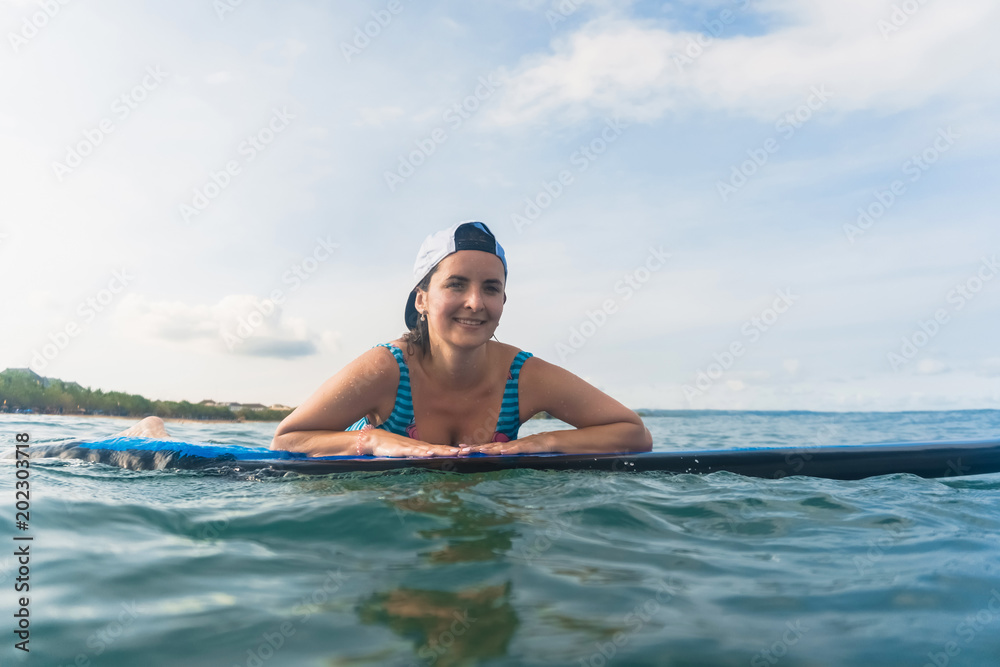 portrait of smiling woman in swimming suit and cap lying on surfing board in ocean portrait of smiling woman in swimming suit and cap lying on surfing board in ocean