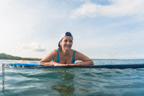 portrait of smiling woman in swimming suit and cap lying on surfing board in ocean © LIGHTFIELD STUDIOS