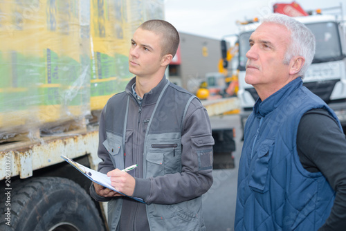 Man with clipboard looking at delivery on lorry