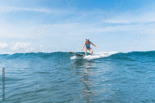 woman in swimming suit and cap surfing in ocean © LIGHTFIELD STUDIOS