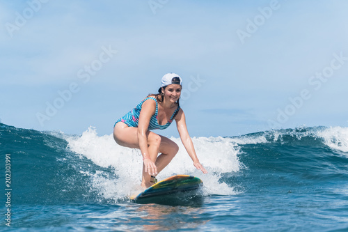 smiling woman in swimming suit surfing in ocean © LIGHTFIELD STUDIOS