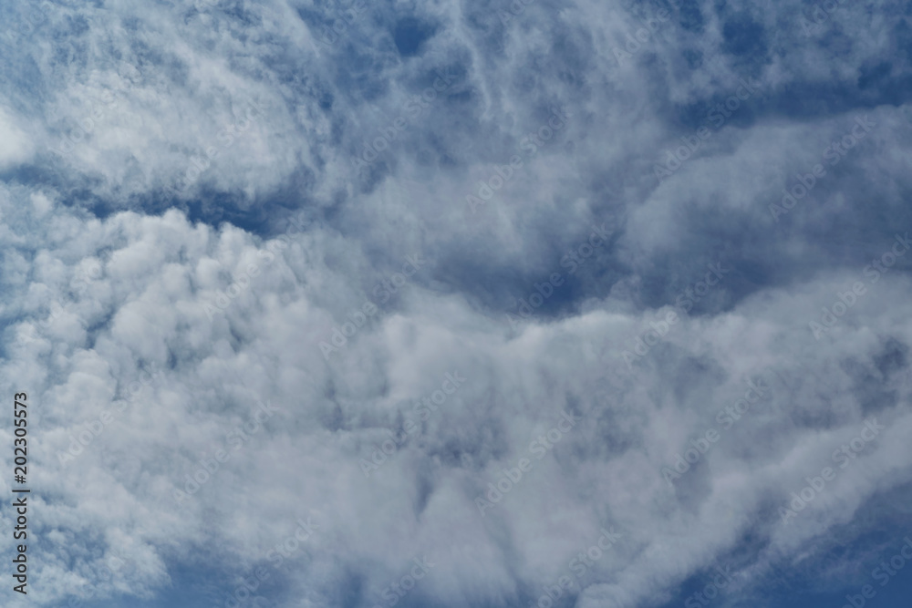 In the pure blue sky, a ragged Cirrus clouds. There are a few small Cumulus clouds. Clouds are arranged in thin layers. Background, backdrop or Wallpaper. In the pure blue sky, a ragged Cirrus clouds. There are a few small Cumulus clouds. Clouds are arranged in thin layers. Background, backdrop or Wallpaper.