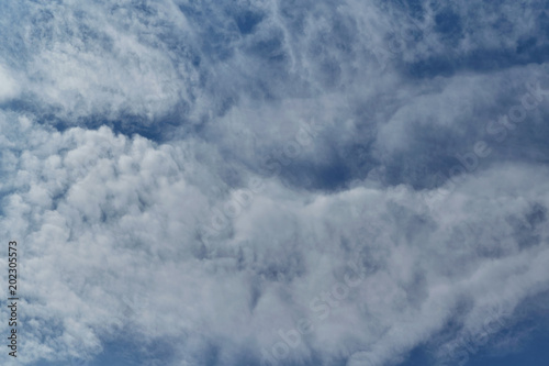 In the pure blue sky, a ragged Cirrus clouds. There are a few small Cumulus clouds. Clouds are arranged in thin layers. Background, backdrop or Wallpaper.