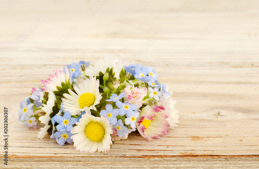 Meadow flowers daisies and forget me not on old desk
