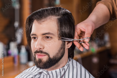 close-up shot of handsome young man getting haircut at barbershop