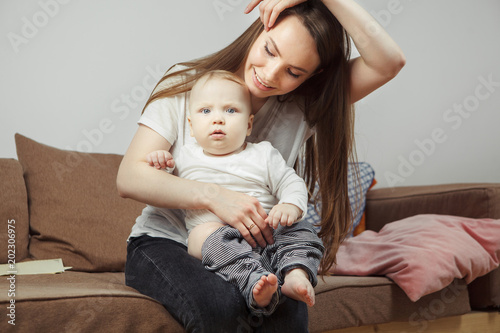 Mother holds on hands her favourite child going to change him clothes.