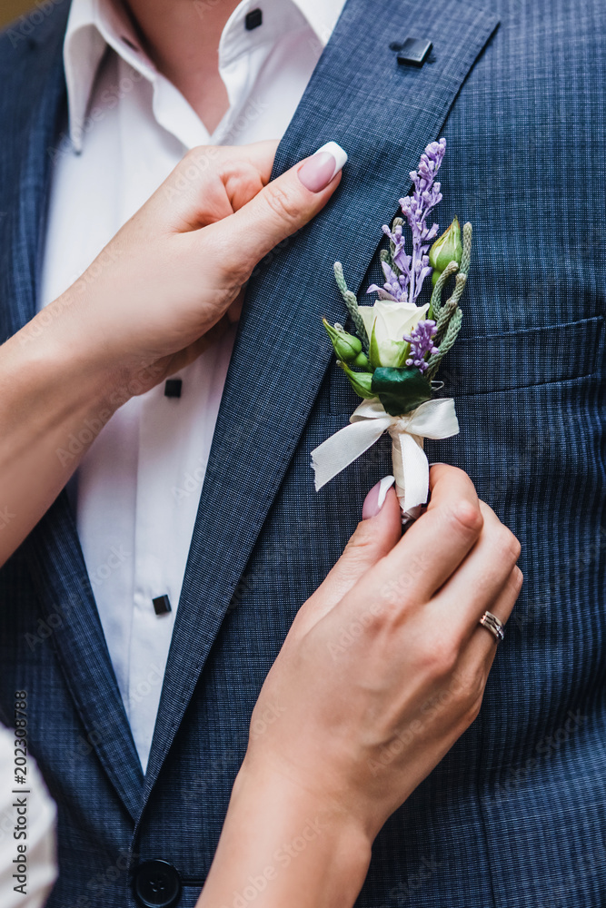 the bride attaches to the groom's costume a flower-shaped boutonniere Stock  Photo | Adobe Stock