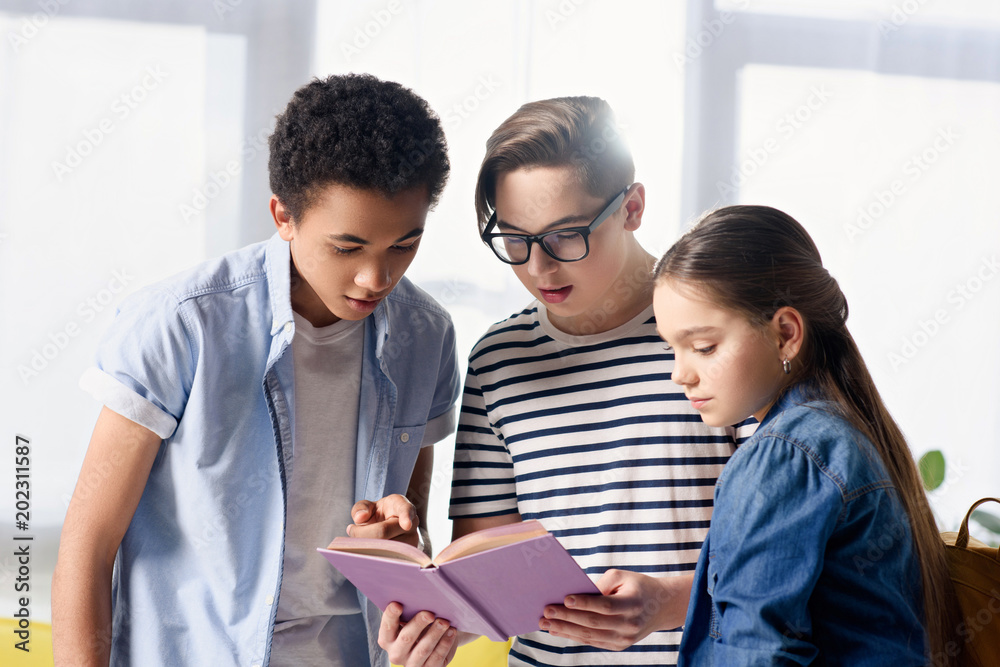 multicultural teenagers looking at book at home multicultural teenagers looking at book at home
