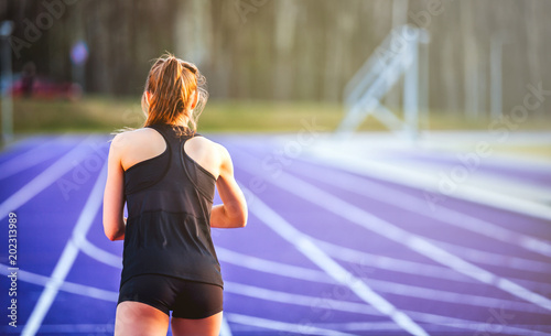 Athletic woman starts training on running track, back view © leszekglasner