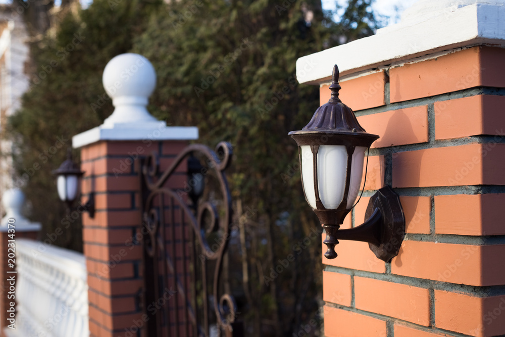 Close Iron Street Lantern On Brick Column Gate Of Modern Style In Garden.