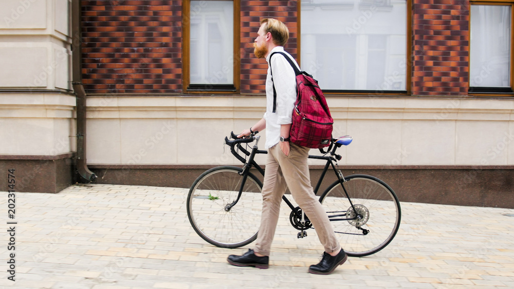 Fototapeta premium Stylish hipster man walking with retro bicycle on street