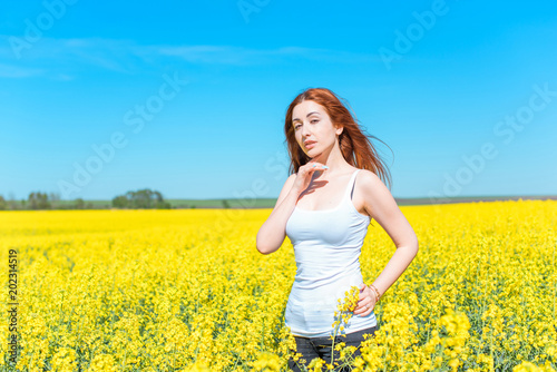 Free relaxed Woman Enjoying Nature. Beauty Girl Outdoor. Freedom concept. Beauty lady with red hair over Sky and Sun. Enjoyment yellow meadow 