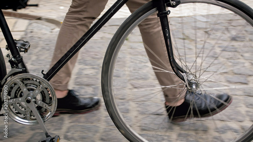 Closeup photo of male feet next to vintage bicycle on paved road