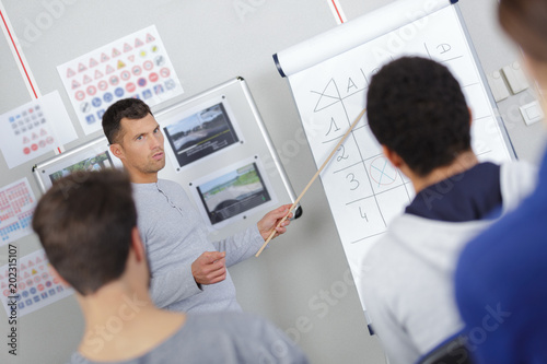 driving instructor pointing at board in a classroom