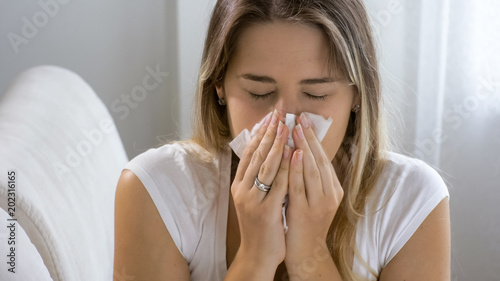 Portrait of sneezing woman in paper tissue