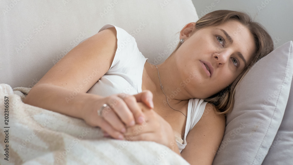 Portrait of upset young woman lying and rubbing hands Portrait of upset young woman lying and rubbing hands