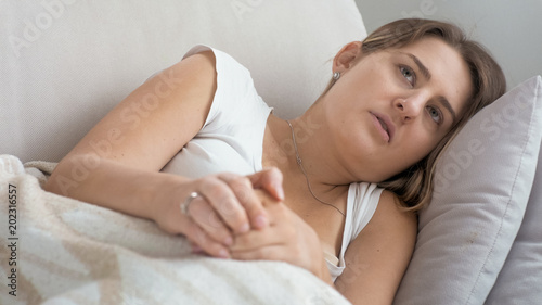 Portrait of upset young woman lying and rubbing hands