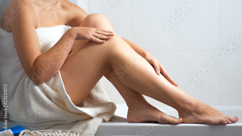 Closeup photo of sexy young woman in bath towel sitting at bathroom photo