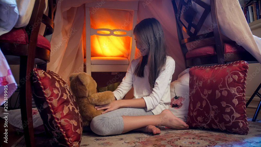 Cute girl in pajamas playing at night with teddy bear