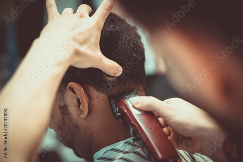 Man having a haircut with a hair clippers. Soft focus. photo