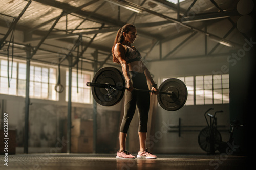 Cross fit woman lifting heavy weights in gym photo