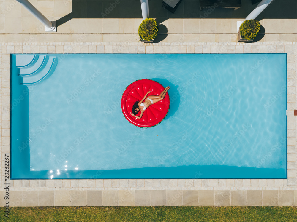 Woman floating on inflatable mattress in pool - obrazy, fototapety, plakaty 