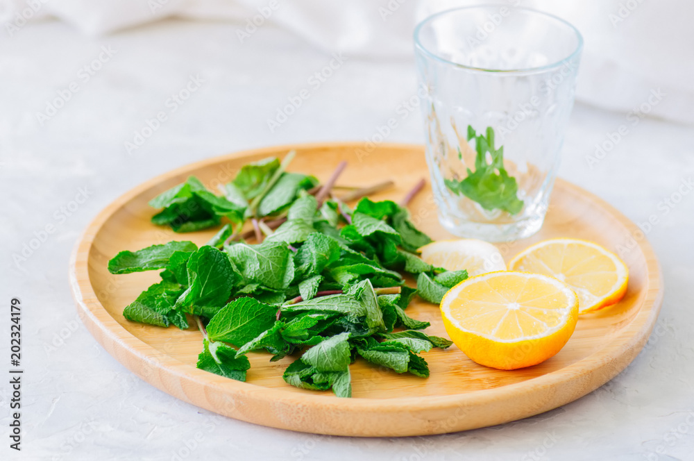Ingredients for moroccan tea or infused water. Mint leaves slices of lemon on a wooden plate. White background. Close up. Ingredients for moroccan tea or infused water. Mint leaves slices of lemon on a wooden plate. White background. Close up.