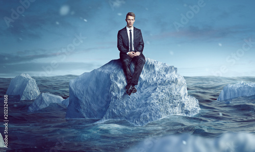 Geschäftsmann sitzt auf Eisberg im Meer