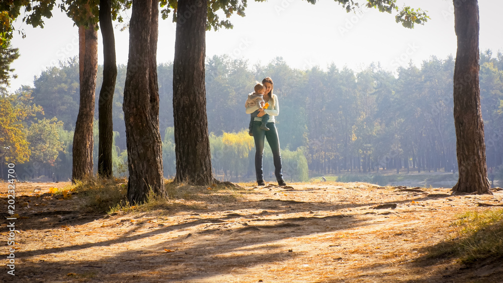 Happy smiling young woman embracing her toddler son at autumn park Happy smiling young woman embracing her toddler son at autumn park