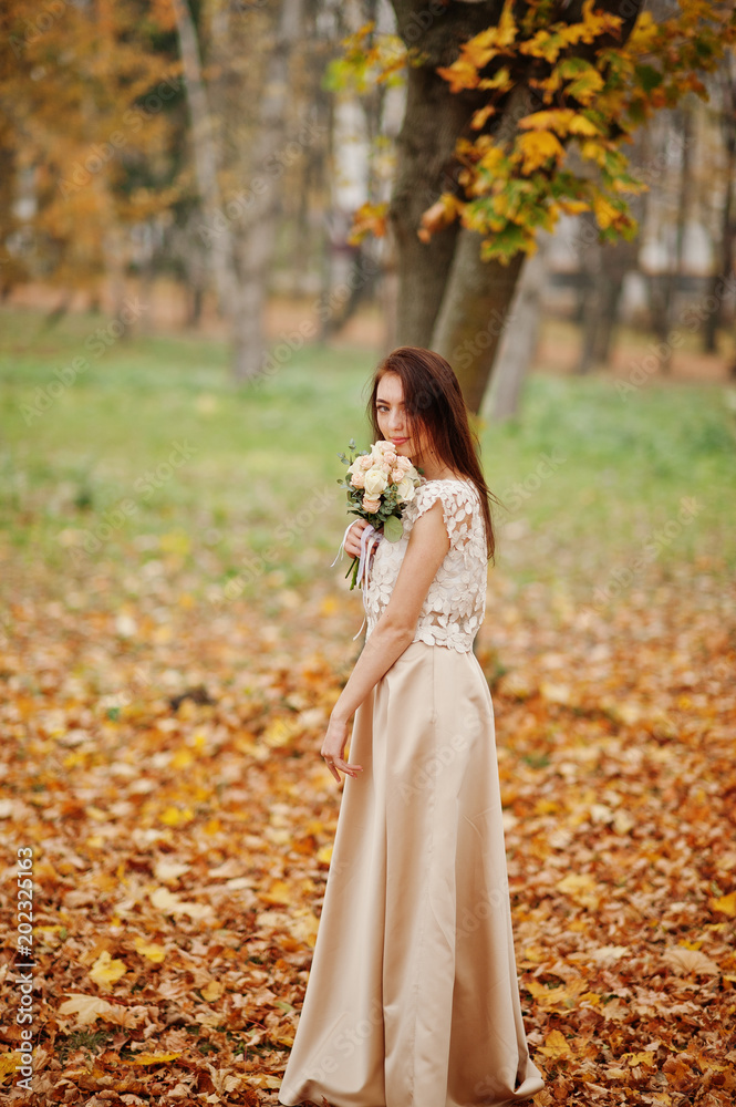 Amazingly girl bridesmaid in golden dress with bouquet at hands at autumn park. Amazingly girl bridesmaid in golden dress with bouquet at hands at autumn park.