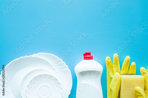Plastic bottle with cleanser, sponge, rubber protective gloves for dish washing up. Housewife cares about kitchen utensil. Daily routine duties. Female's home responsibilities. Empty place for text.