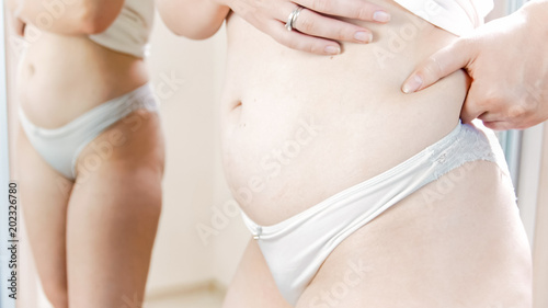Closeup photo of young woman touching fat on her waist © Кирилл Рыжов