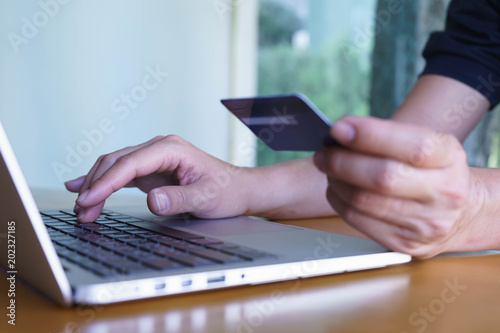 Man's hands holding credit card and typing on the keyboard of laptop, onine shopping, online payment.
