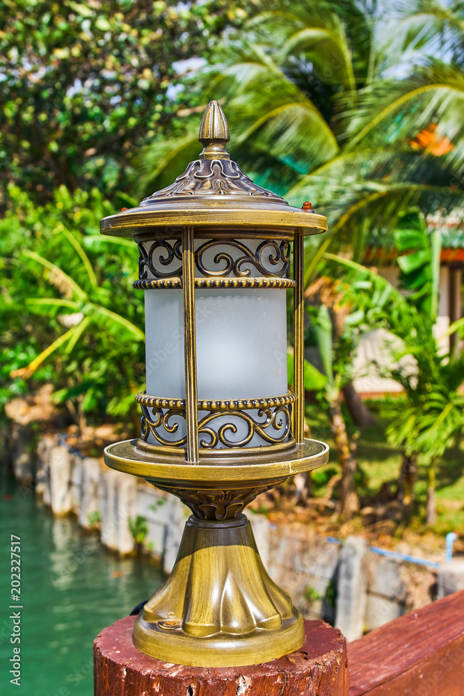 Nice bronze lantern on tropical wooden bridge through the river Nice bronze lantern on tropical wooden bridge through the river