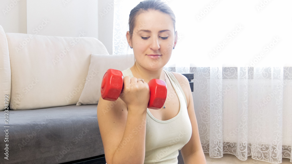 Portrait of young woman loosing weight by exercising with dumbbells Portrait of young woman loosing weight by exercising with dumbbells